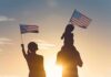 Trump Crackdown Bites — Migration Pipeline Cools Silhouettes of a family waving American flags at sunset