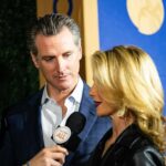 Gavin Newsom and Jennifer Siebel Newsom speak into a microphone at an event