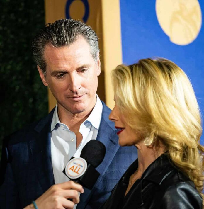shutterstock_1585339564 Gavin Newsom and Jennifer Siebel Newsom speak into a microphone at an event