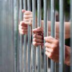 Hands gripping jail bars