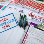 Voter Rolls Exposed — Prison Warnings Fly Voter registration table with forms, pens, and informational materials
