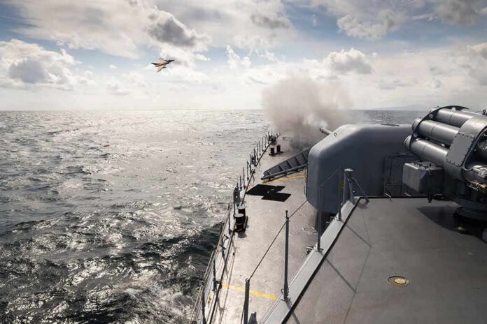 naval warship firing deck gun at sea