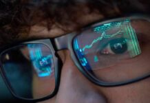 Tech Titans Tip S&P – Inflate A Ticking Risk Close-up of a persons eyes with financial data reflected in their glasses