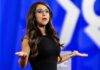 Capitol Scandal Claims – Boebert Fights Back Woman speaking on stage with arms outstretched