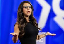 Capitol Scandal Claims – Boebert Fights Back Woman speaking on stage with arms outstretched