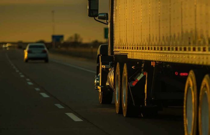 shutterstock_2289923583 Semi-truck trailer driving on highway at sunset