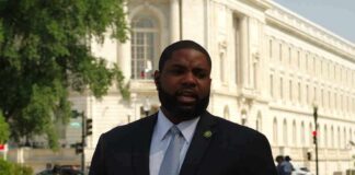Man in a suit speaking outside a neoclassical government building