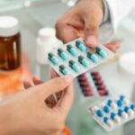 Hands exchanging a blister pack of capsules at a pharmacy counter