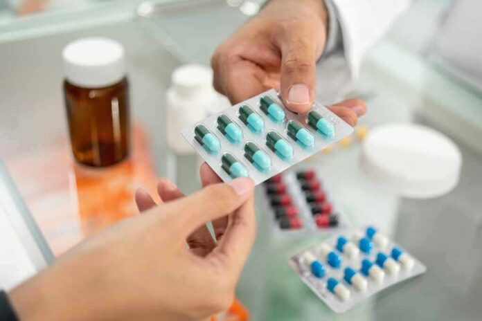 Hands exchanging a blister pack of capsules at a pharmacy counter
