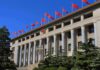 Markets Breathe – Trade Truce Extended Grand government building with columns and red flags