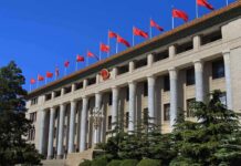 Grand government building with columns and red flags