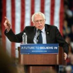 elderly man speaking at podium during rally