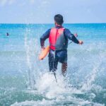 Blood In Shallows: Dad Protects Pregnant Fiancée lifeguard wading into ocean with rescue buoy