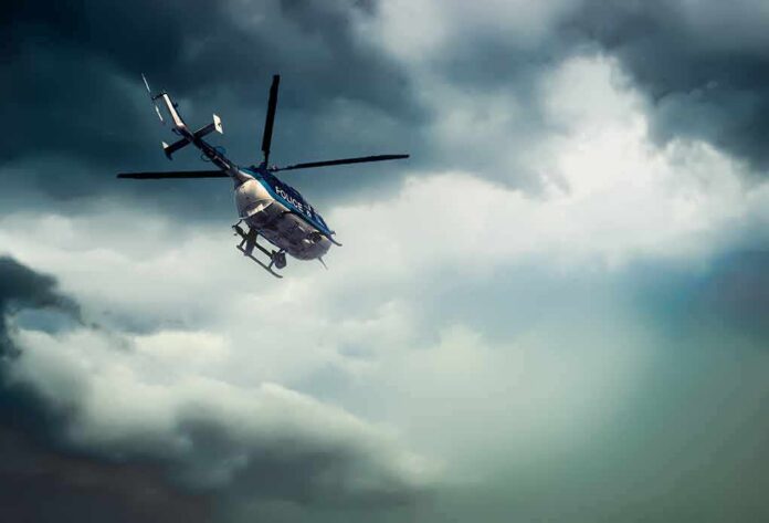Police helicopter flying under dark storm clouds