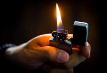 Hand holding a lit metal lighter