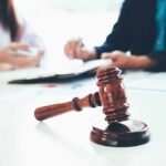 Big Oil Panic: One County, National Rules? judge's gavel on table with people discussing documents in background