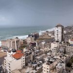 Coastal city skyline with mid-rise buildings by a rough sea under overcast skies