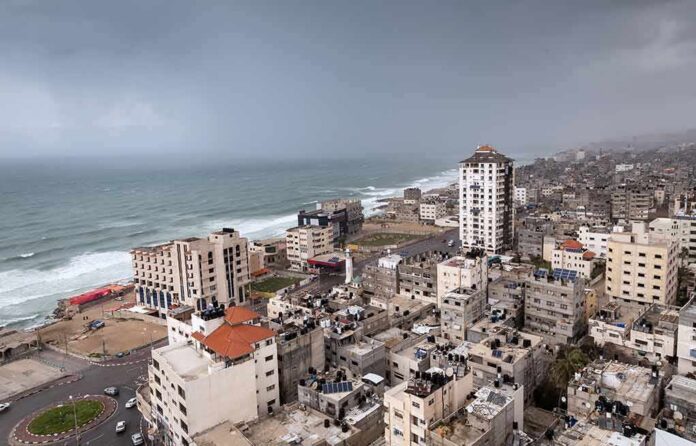 shutterstock_1340771222 Coastal city skyline with mid-rise buildings by a rough sea under overcast skies