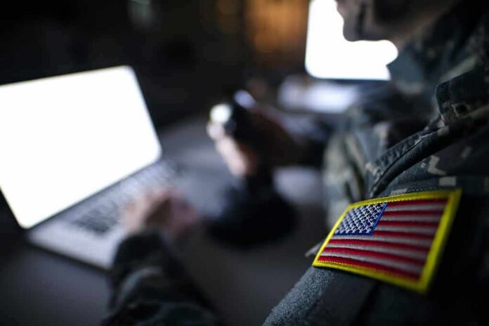 Soldier with U.S. flag patch using a laptop in a dim room
