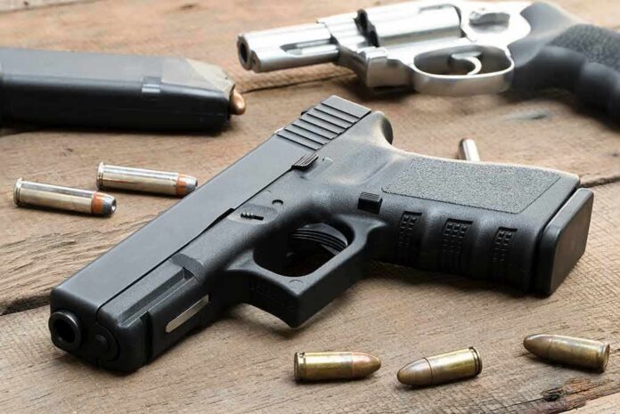 shutterstock_1438926476 Handguns and ammunition on a wooden surface