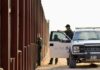 Border patrol agents near a tall fence and a marked pickup truck
