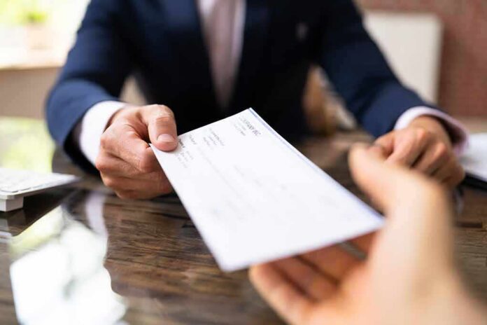 Businessperson handing over a check across a desk