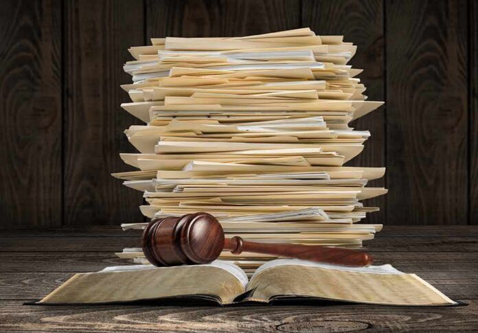 shutterstock_2183204635 Stack of file folders with a judge's gavel on an open book