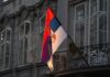Election Shock: Students Seize Parliament Serbian flag on a building facade