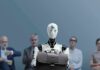 World Bank Alarm: Inequality Set To Spike Jan-Peter Nikiferow seated with a humanoid robot holding a briefcase in front