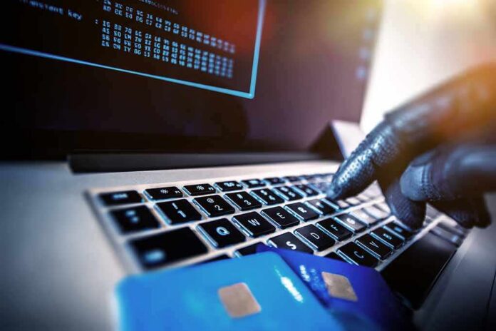 shutterstock_360575702 Gloved hand typing on laptop keyboard with credit cards nearby