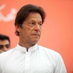 Police Wall Off Islamabad As Convoys Advance Imran Khan in a white kurta looking to the side against an orange background