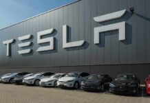 Tesla cars parked outside a large Tesla building