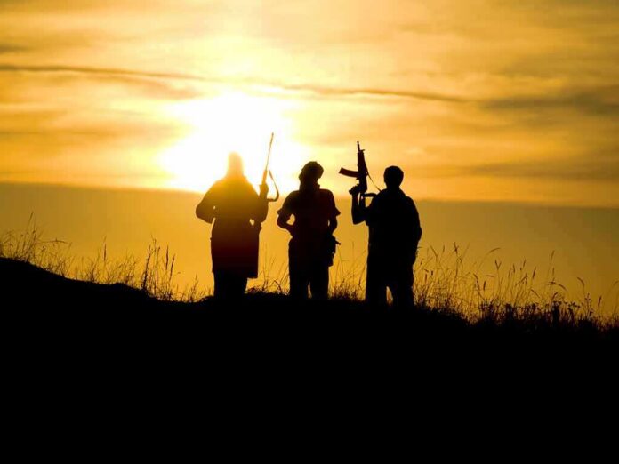 silhouettes of three armed people at sunset