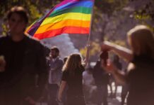 Person holding a rainbow flag at an outdoor gathering